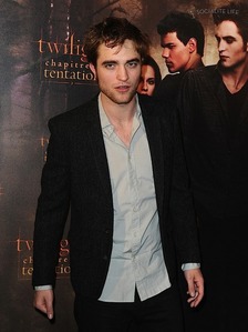  my Robert on the red carpet in front of a دیوار with a poster of New Moon behind him<3