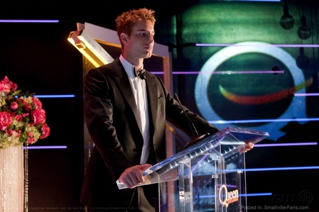  Justin on stage, holding a speech at the Queen Industries shareholder meeting in "Echo" (the part where he's standing is elevated, hope that counts as a stage)