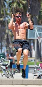  Kellan holding onto a set of rings as he works out on the beach<3