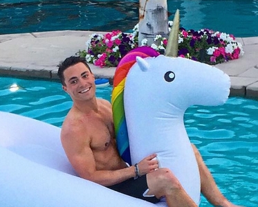 Colton on a unicorn pool floatie with a rainbow mane