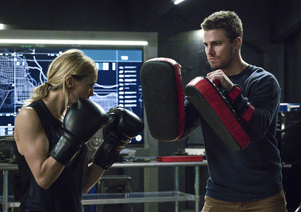Katie Cassidy throwing a punch at Stephen Amell 