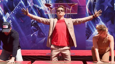 RDJ raising his hands from the Avengers cast handprint ceremony last jaar