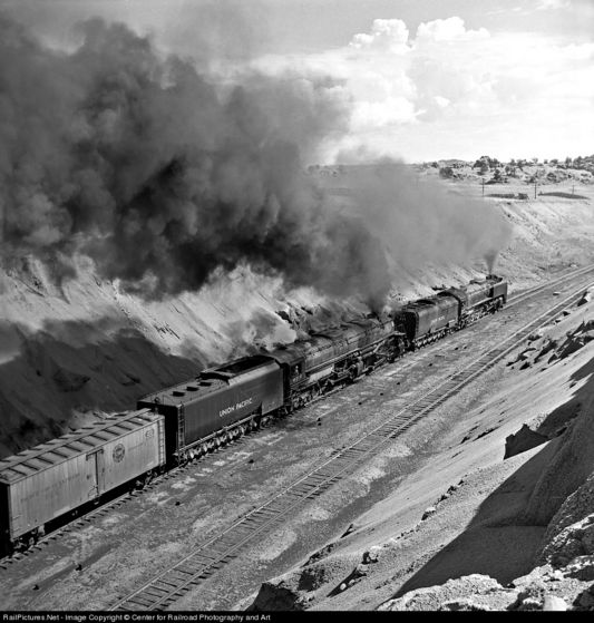  One of Union Pacific's largest steam engines pulls a train up a colline with some help from a smaller one.