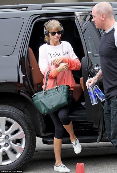 Protection: Taylor was accompanied by a burly bodyguard carrying water ahead of her intense workout  k