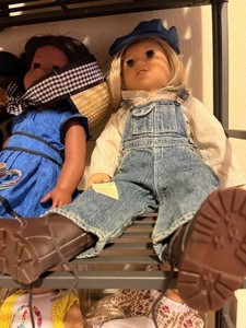Kit’s hand-me-down bib overalls and striped shirt help disguise her as a boy! Cover her head with a blue cap from her hobo friend Will.
