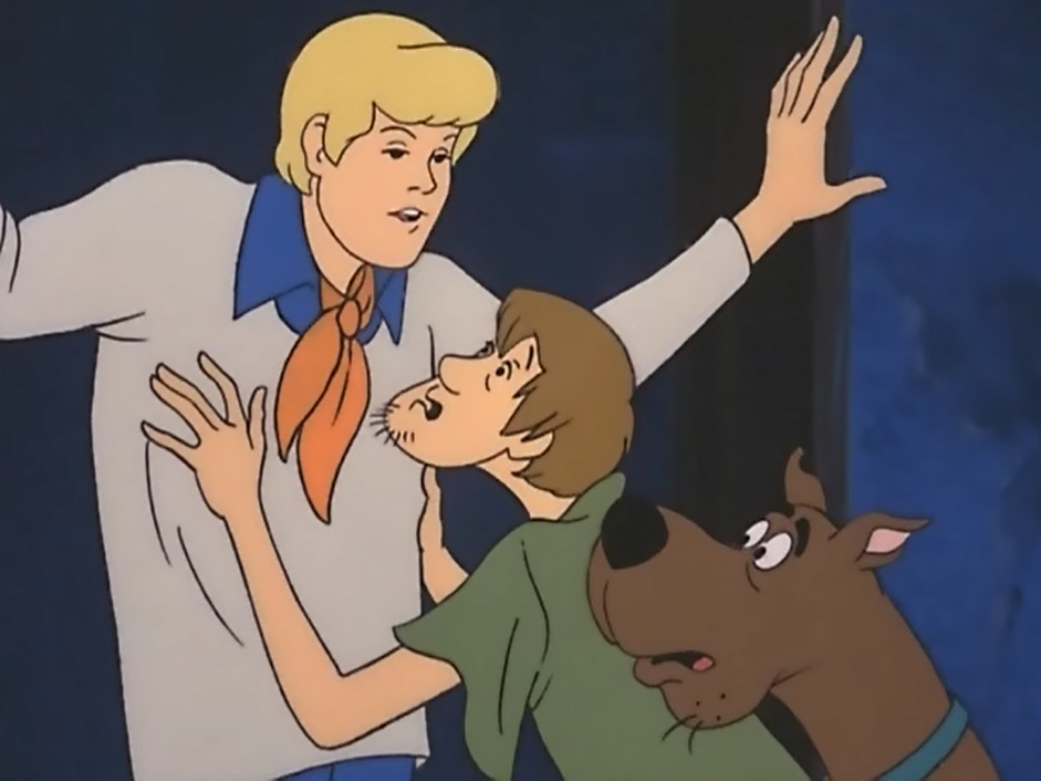 Fred prevents Shaggy and Scooby from running out on the mystery. 