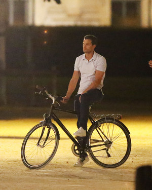 Jamie riding a bike along the streets of Paris for Fifty Shades Freed