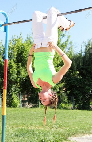  girl hanging upside down in a park and laughing