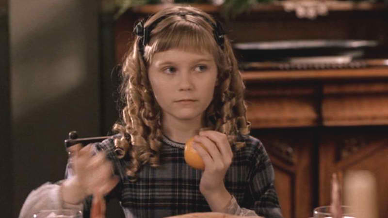 a still from the 1996 Little Women film showing Kirsten Dunst as Amy March, holding an orange