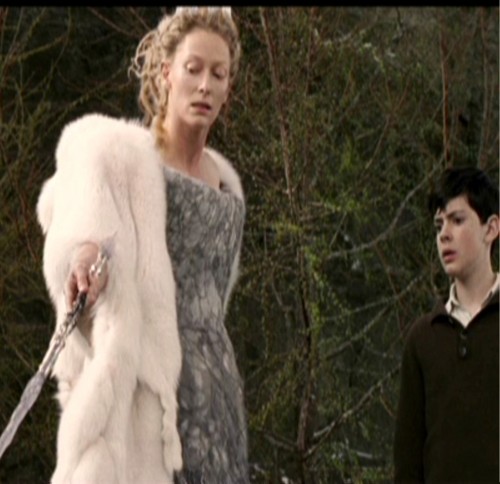 Jadis points her wand at the fox Edmund looks on.
