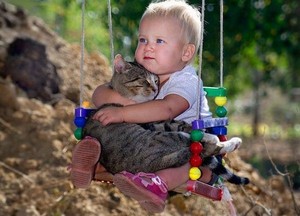Baby Playing With A Cat While On The Swing