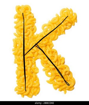 Letter K of the English alphabet from dry pasta on a white